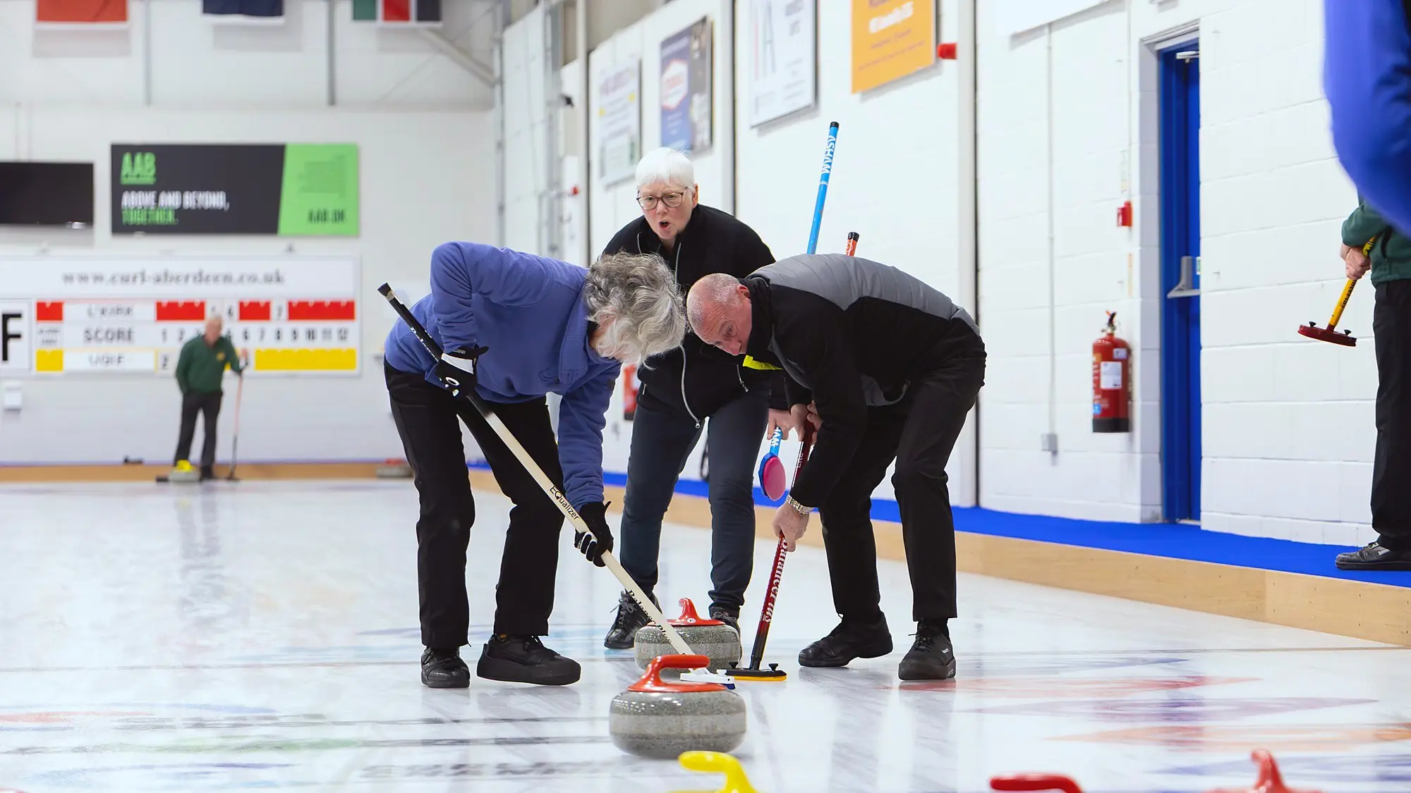 Curlers sweeping a stone at Curl Aberdeen
